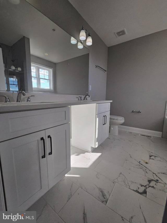 bathroom featuring marble finish floor, double vanity, a sink, and visible vents