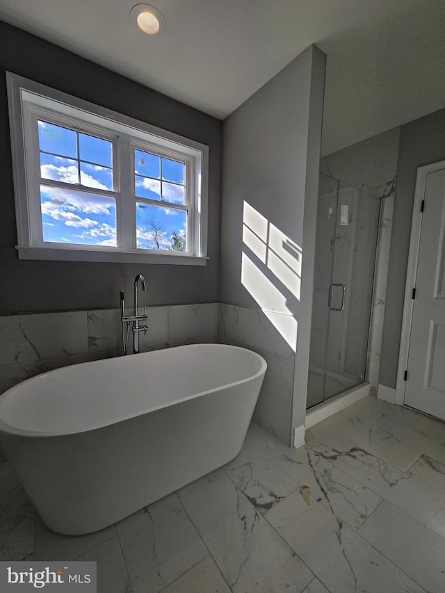 bathroom featuring marble finish floor, a freestanding tub, and a shower stall