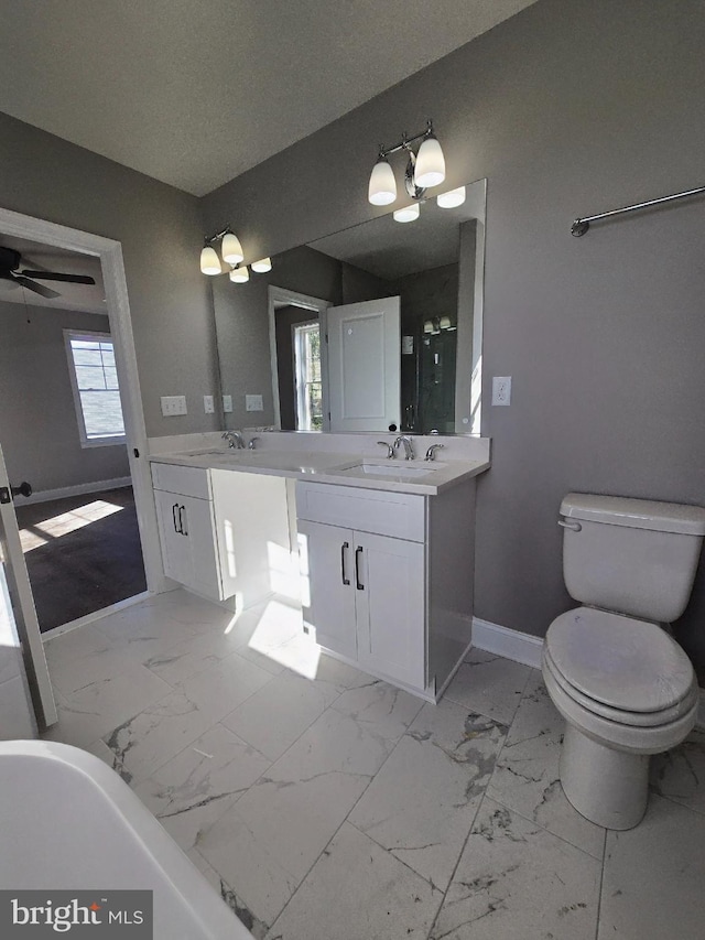 full bathroom featuring toilet, a sink, baseboards, marble finish floor, and double vanity