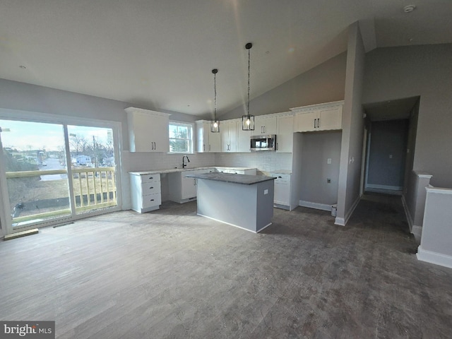 kitchen with stainless steel microwave, white cabinets, decorative backsplash, and a center island