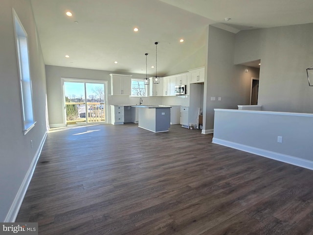 unfurnished living room featuring high vaulted ceiling, baseboards, dark wood-type flooring, and recessed lighting