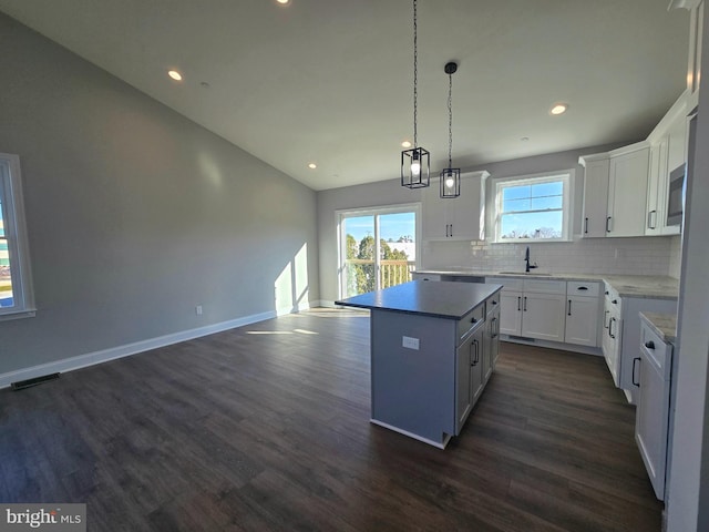 kitchen with a kitchen island, dark wood-style flooring, decorative backsplash, and a sink