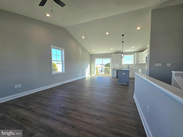 unfurnished living room featuring baseboards, recessed lighting, dark wood-style floors, and a healthy amount of sunlight