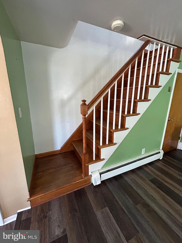 stairway with a baseboard radiator, baseboards, and wood finished floors