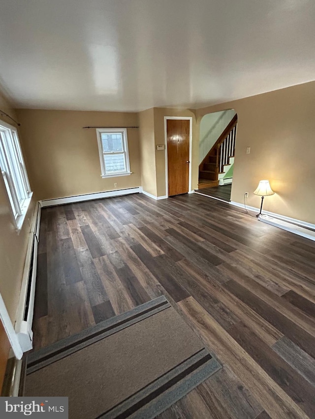 unfurnished living room with a baseboard radiator, stairs, baseboards, and wood finished floors