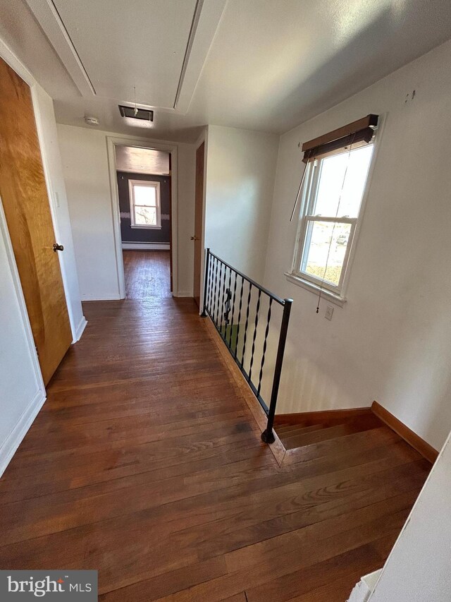 hall featuring visible vents, attic access, an upstairs landing, wood finished floors, and baseboards