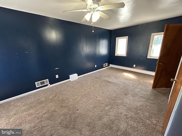 unfurnished room with carpet floors, a ceiling fan, visible vents, baseboards, and baseboard heating