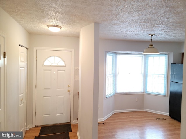 foyer entrance with a textured ceiling and light hardwood / wood-style floors