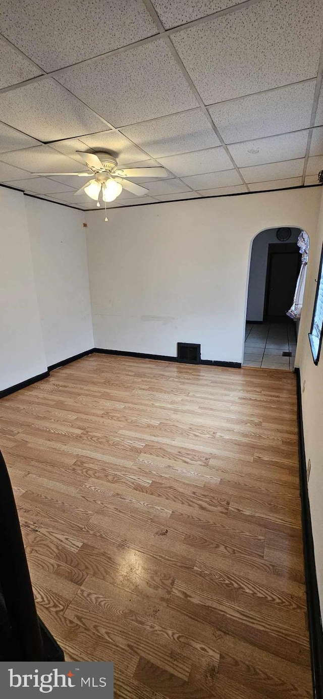 spare room featuring ceiling fan, hardwood / wood-style flooring, and a drop ceiling