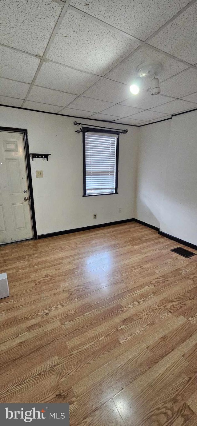 unfurnished room featuring a drop ceiling and light hardwood / wood-style floors