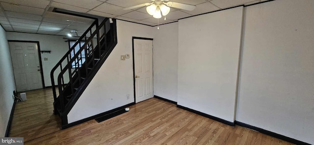 basement with ceiling fan, hardwood / wood-style flooring, and a drop ceiling