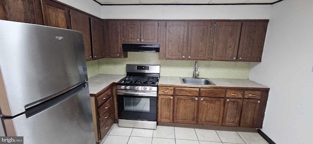 kitchen with appliances with stainless steel finishes, light tile patterned flooring, dark brown cabinets, and sink