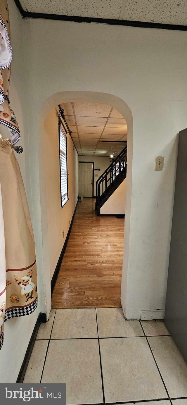 corridor with a paneled ceiling and tile patterned floors