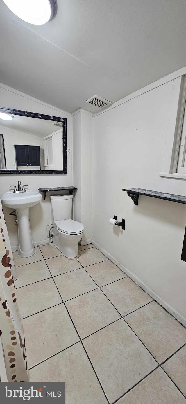 bathroom with toilet, tile patterned floors, and sink