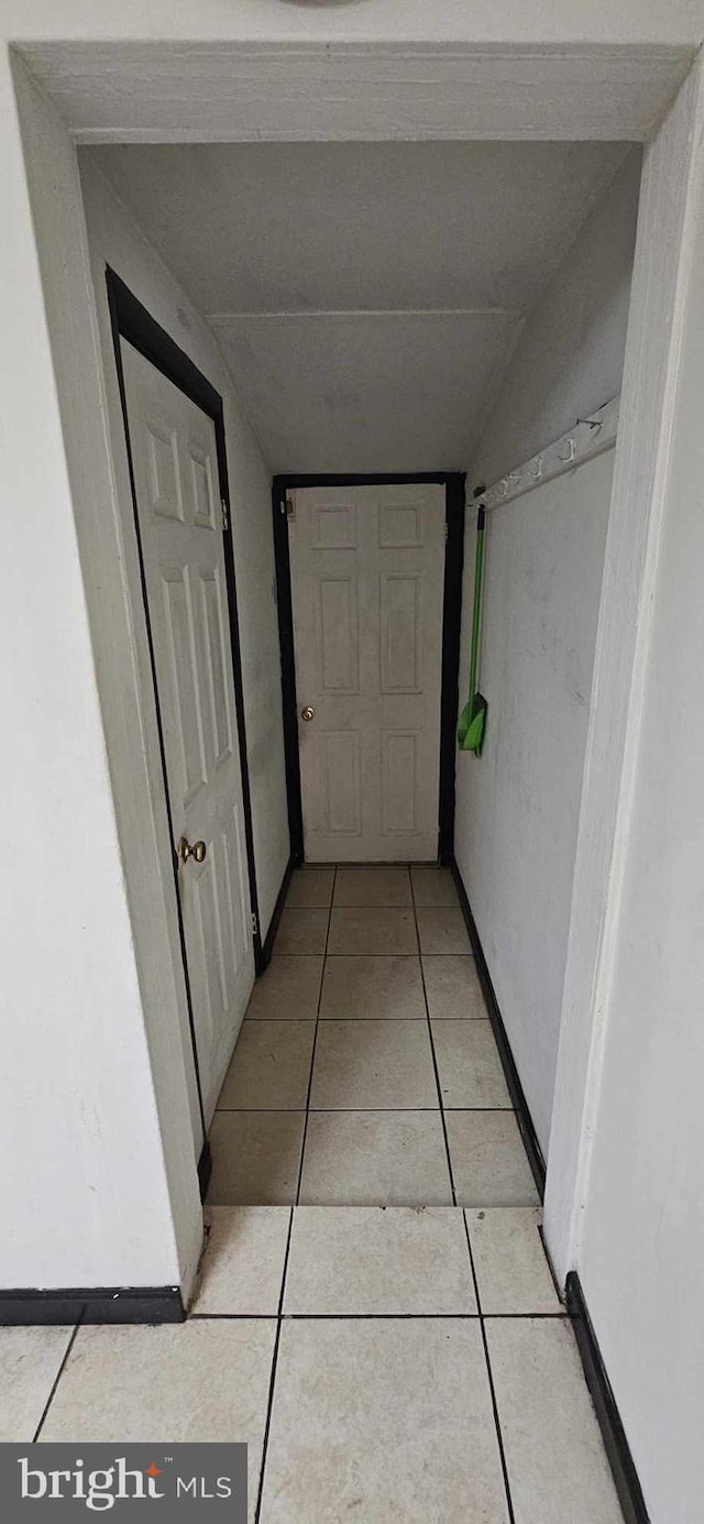 hallway with lofted ceiling and light tile patterned floors