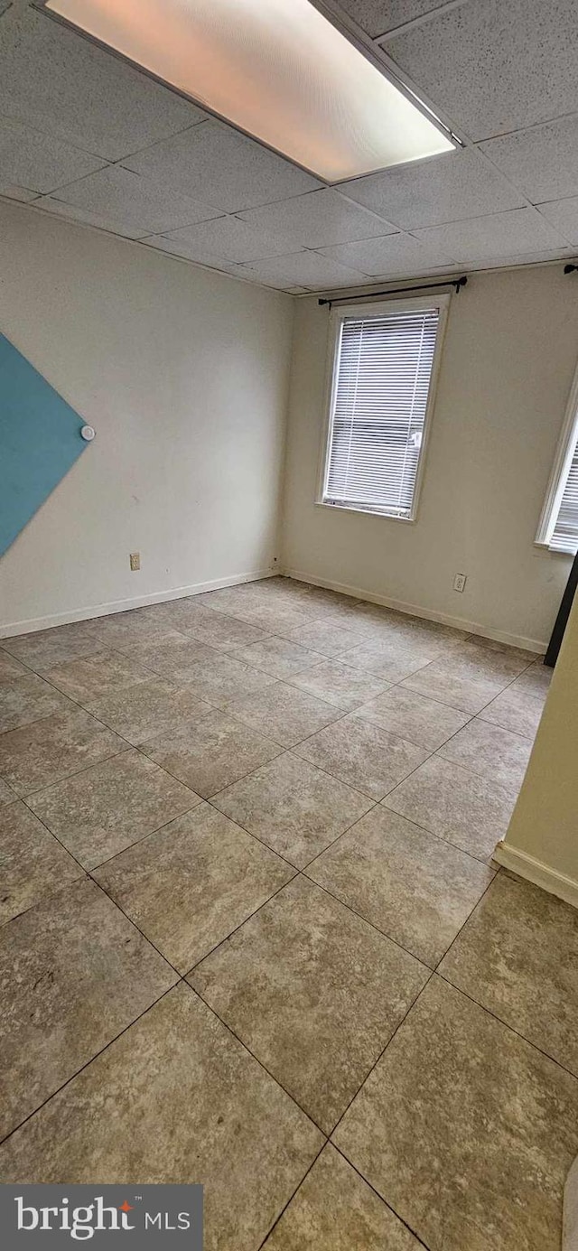 unfurnished room featuring a healthy amount of sunlight and a drop ceiling