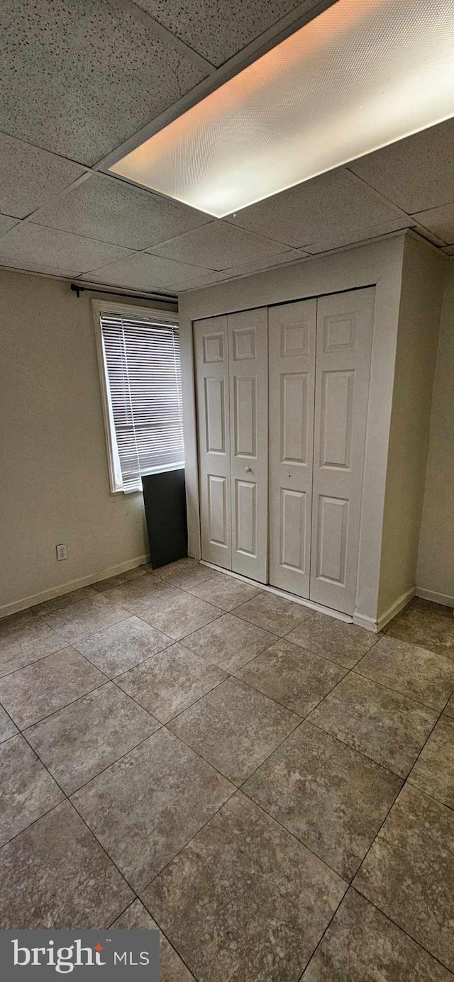 unfurnished bedroom featuring a closet and a drop ceiling