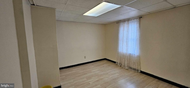 unfurnished room with light hardwood / wood-style floors and a paneled ceiling