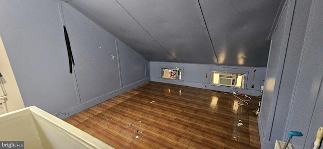 bonus room featuring dark wood-type flooring, vaulted ceiling, and a wall unit AC