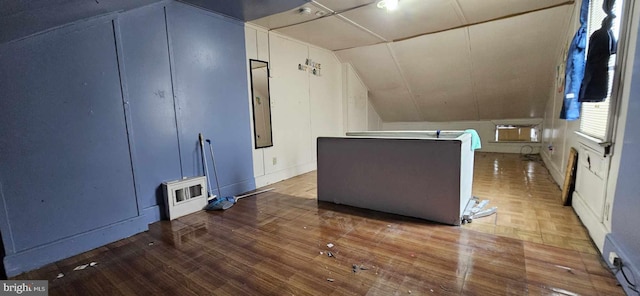 additional living space with an AC wall unit, vaulted ceiling, and wood-type flooring