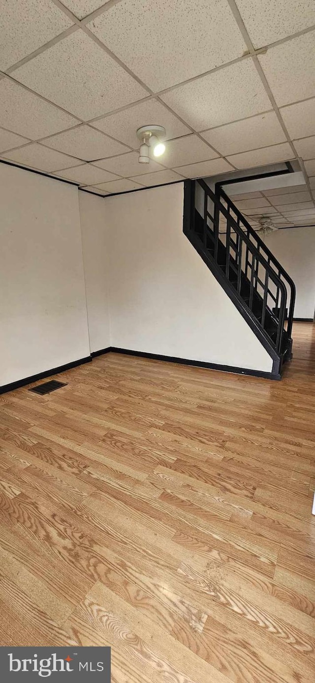 basement with light hardwood / wood-style floors and a paneled ceiling