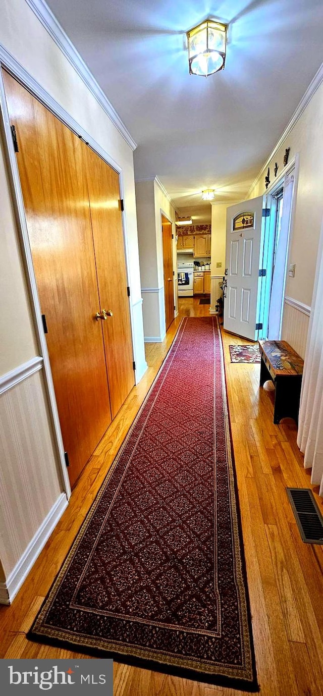 hall featuring wainscoting, crown molding, visible vents, and hardwood / wood-style floors