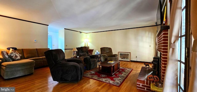 home theater room with ornamental molding, a fireplace, baseboards, and wood finished floors