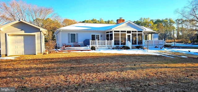 view of front of home with a chimney, a lawn, a sunroom, a garage, and an outdoor structure