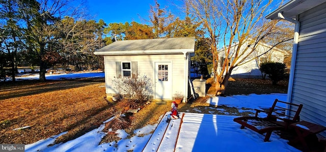 snow covered structure with a shed and an outdoor structure