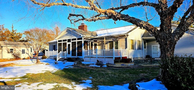 view of front of home featuring a yard, a chimney, and a sunroom