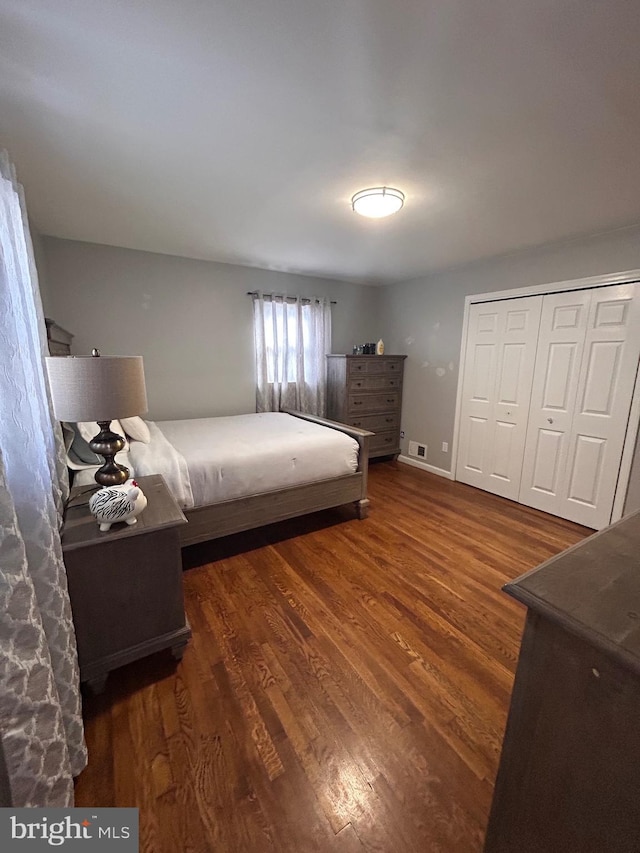 bedroom with dark wood-type flooring and a closet