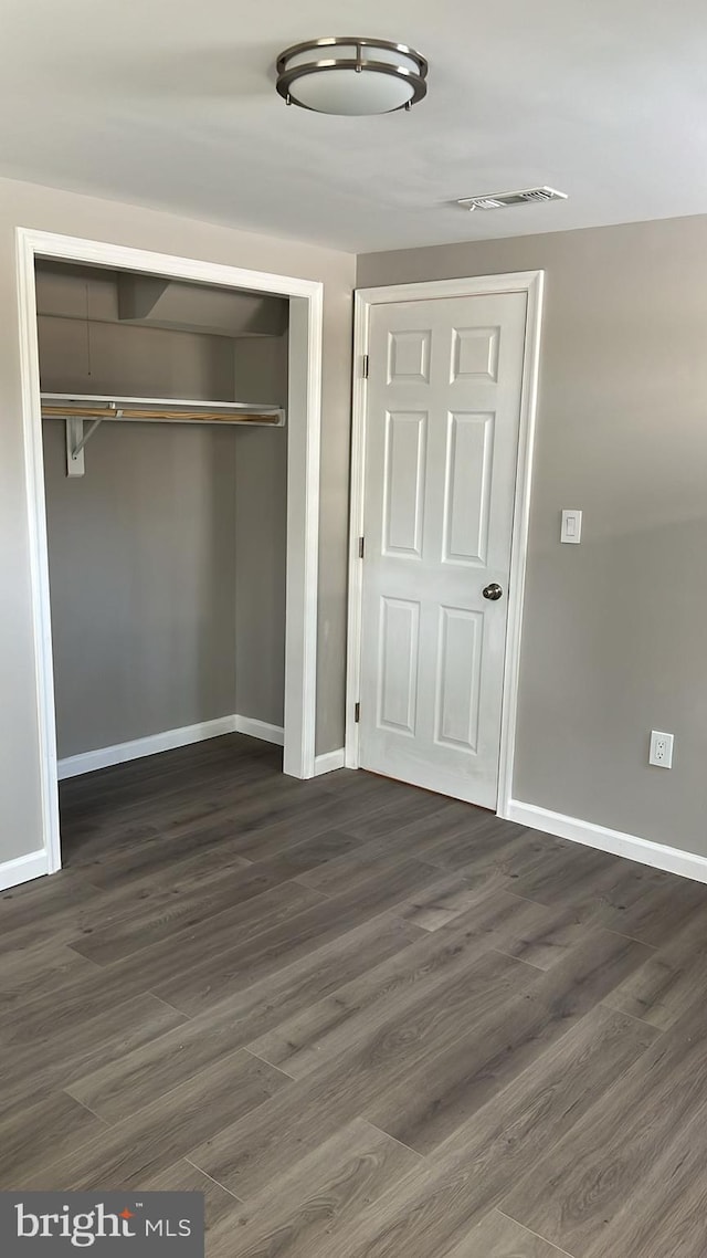 unfurnished bedroom featuring a closet and dark hardwood / wood-style flooring