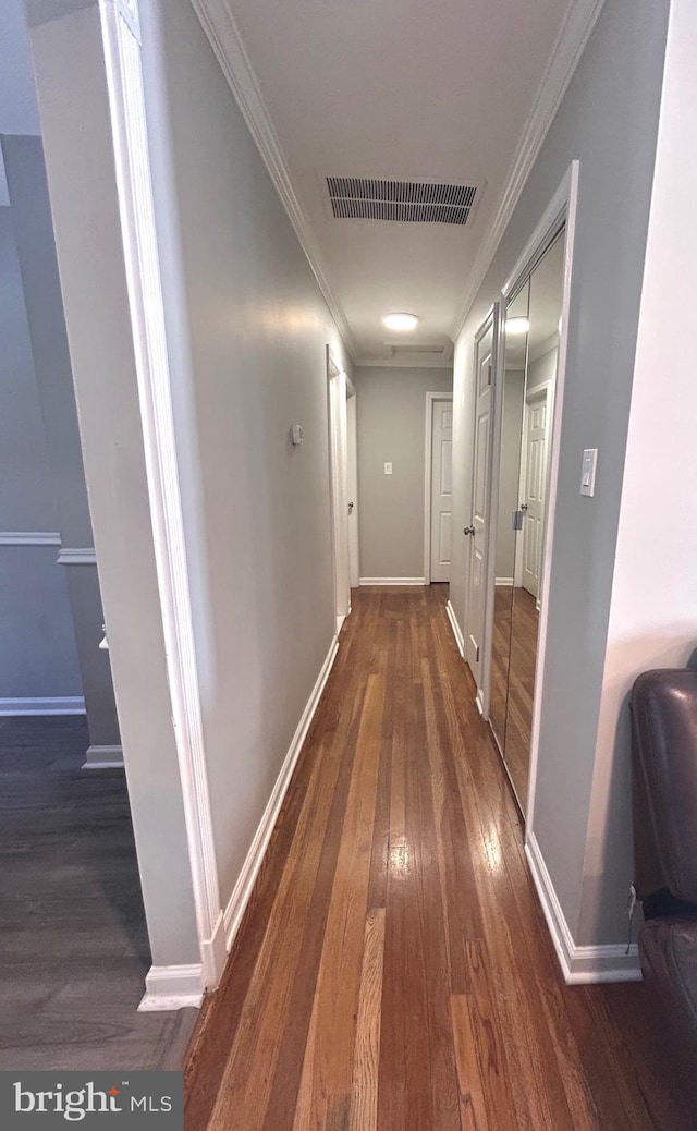 corridor with dark hardwood / wood-style flooring and ornamental molding