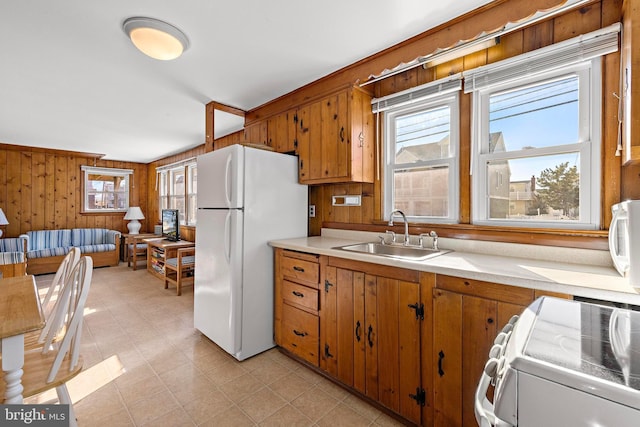 kitchen with sink, white appliances, and wood walls