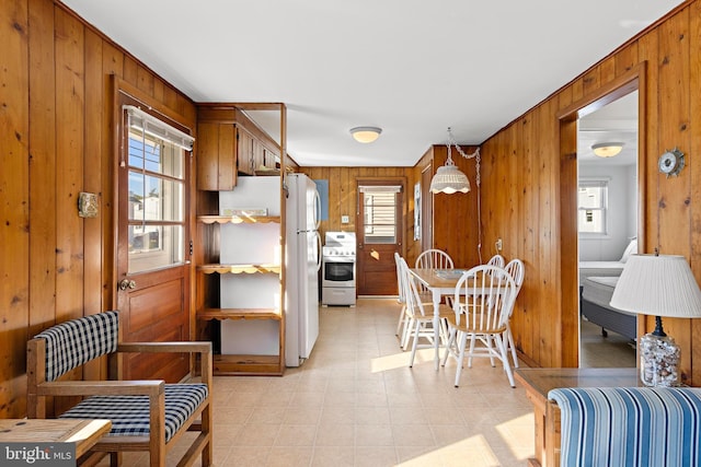 kitchen featuring wooden walls, stainless steel stove, pendant lighting, and white fridge