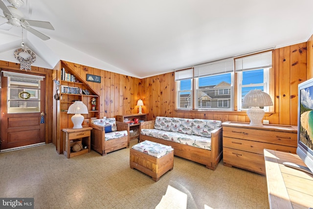 living room featuring wooden walls, ceiling fan, and vaulted ceiling