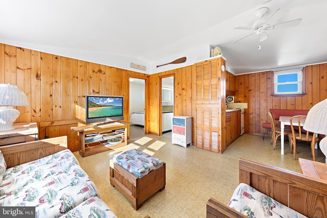 living room with ceiling fan, wood walls, and vaulted ceiling