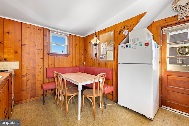 dining room with breakfast area, wood walls, and vaulted ceiling