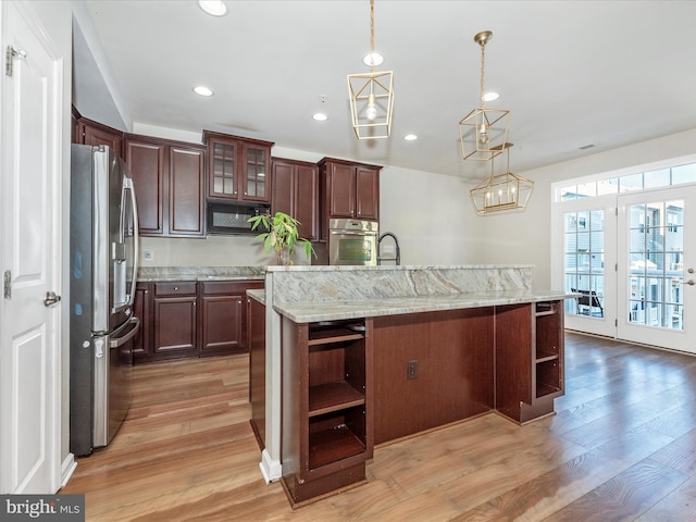 kitchen with decorative light fixtures, appliances with stainless steel finishes, and a kitchen island with sink