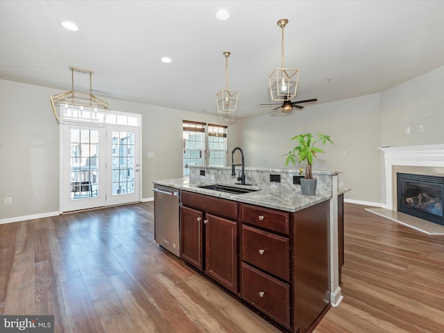 kitchen featuring pendant lighting, dishwasher, sink, dark wood-type flooring, and light stone countertops