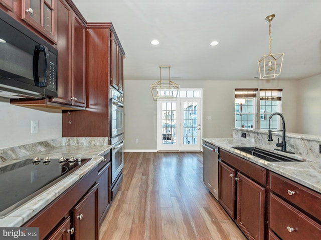 kitchen with sink, pendant lighting, black appliances, and light hardwood / wood-style flooring