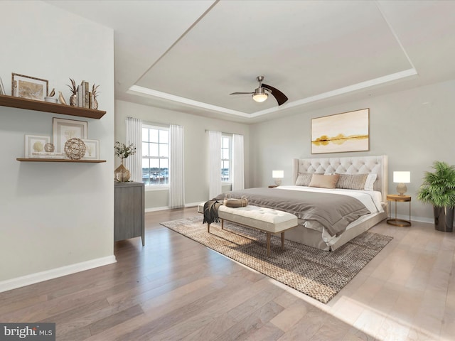 bedroom with ceiling fan, a raised ceiling, and hardwood / wood-style flooring