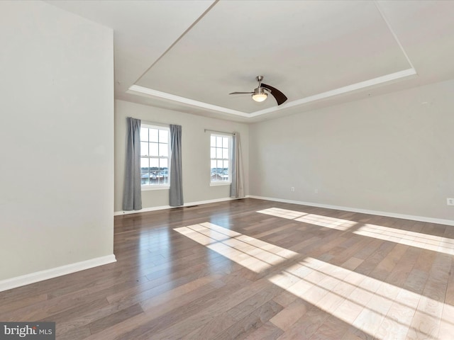 spare room with hardwood / wood-style flooring, ceiling fan, and a raised ceiling