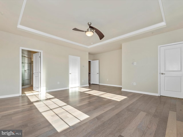 unfurnished bedroom featuring ceiling fan, hardwood / wood-style flooring, and a tray ceiling