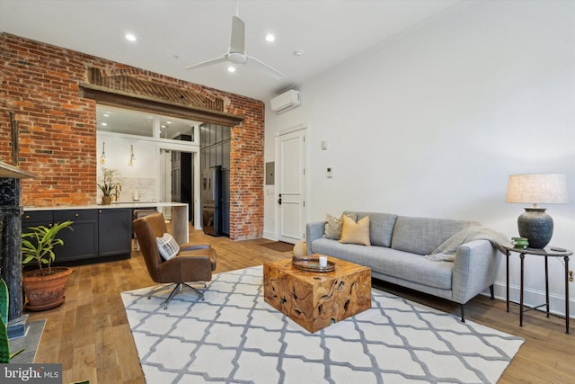 living room featuring brick wall, an AC wall unit, ceiling fan, and light hardwood / wood-style floors