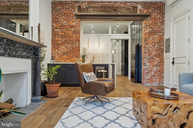 sitting room featuring sink, light wood-type flooring, and brick wall