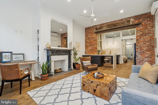 living room featuring ceiling fan, a wall unit AC, light wood-type flooring, and brick wall