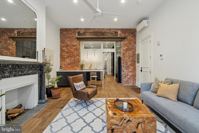 living room featuring a wall mounted AC, brick wall, hardwood / wood-style floors, ceiling fan, and sink