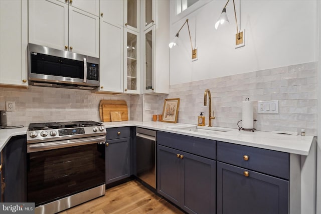 kitchen featuring stainless steel appliances, white cabinetry, sink, and tasteful backsplash