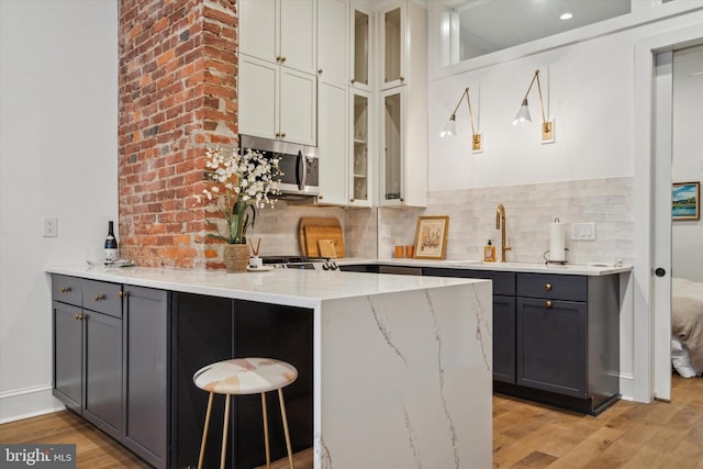 kitchen with sink, light wood-type flooring, gray cabinetry, and white cabinetry